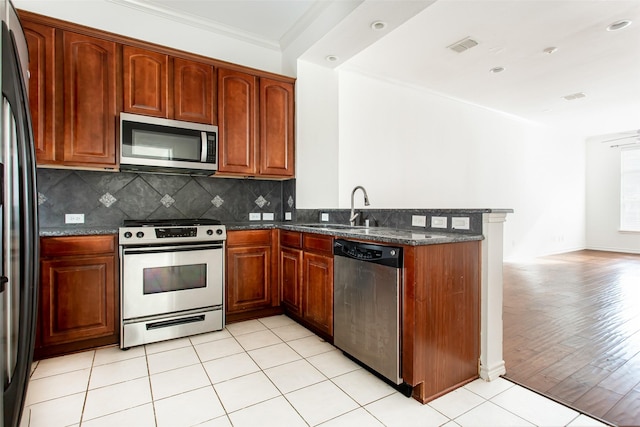 kitchen with decorative backsplash, a sink, a peninsula, ornamental molding, and stainless steel appliances