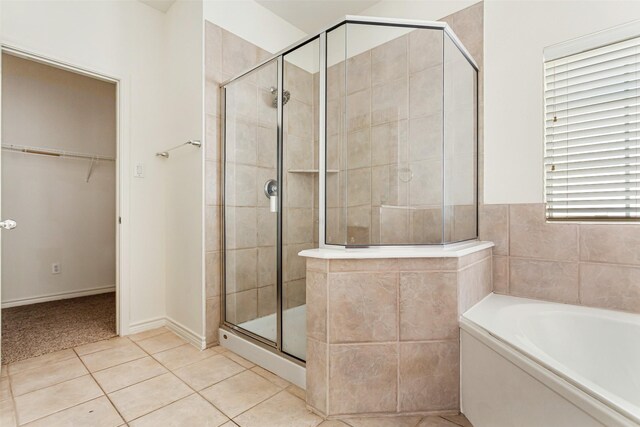 full bath featuring a garden tub, a walk in closet, tile patterned flooring, and a shower stall