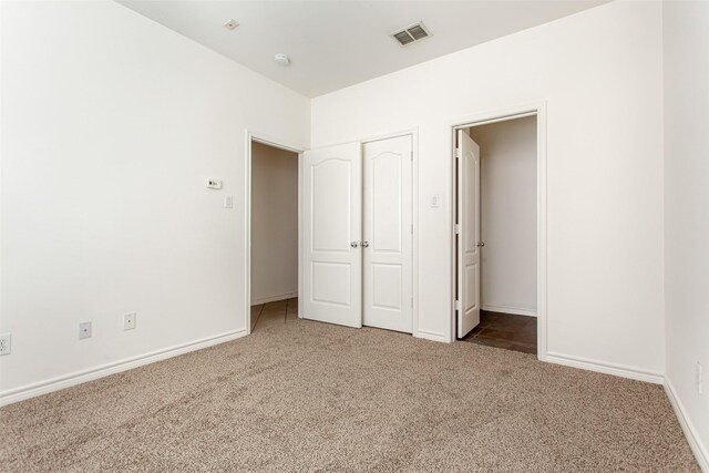 unfurnished bedroom featuring baseboards, carpet, and visible vents