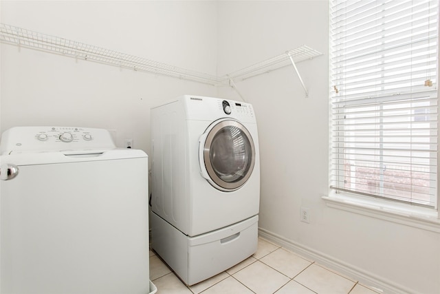 washroom featuring baseboards, separate washer and dryer, laundry area, and light tile patterned floors