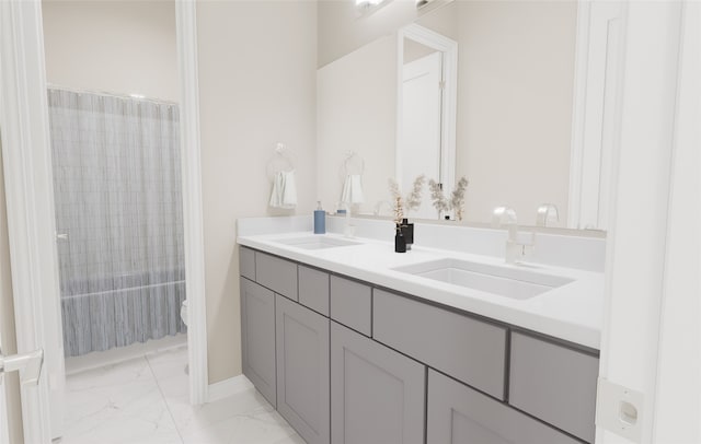 full bath with double vanity, a sink, marble finish floor, and toilet