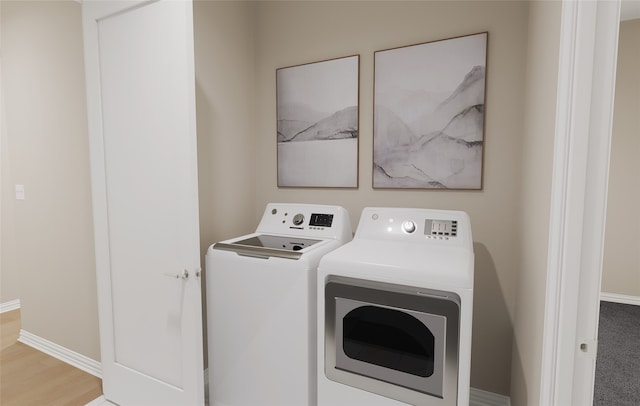 washroom featuring washing machine and clothes dryer, baseboards, light wood-style flooring, and laundry area