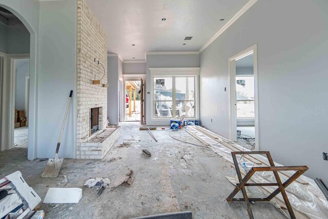3406 Woodlake Dr, Granbury, TX 76048 - unfurnished living room with crown molding, arched walkways, and a fireplace
