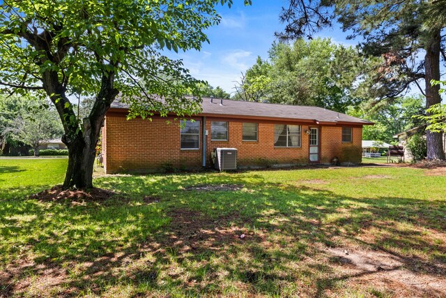 rear view of property with brick siding, a yard, and cooling unit