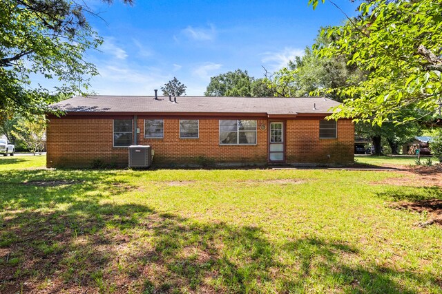 rear view of property with a lawn, brick siding, and cooling unit