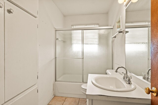 bathroom featuring vanity, enclosed tub / shower combo, tile patterned floors, and toilet