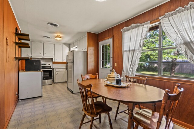 dining area with visible vents, wood walls, and light floors