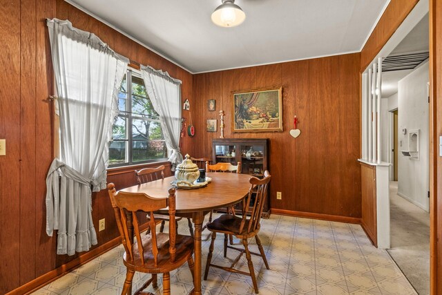 dining room with light floors and wood walls