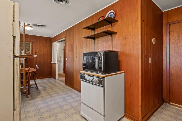 kitchen featuring visible vents, wood walls, open shelves, black microwave, and light floors
