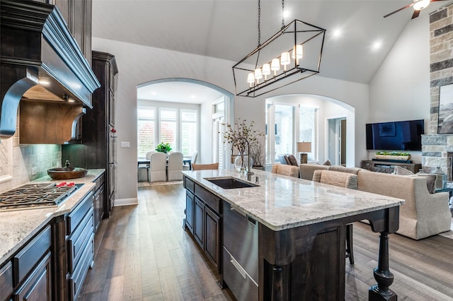 kitchen with arched walkways, dark wood-style floors, and a sink