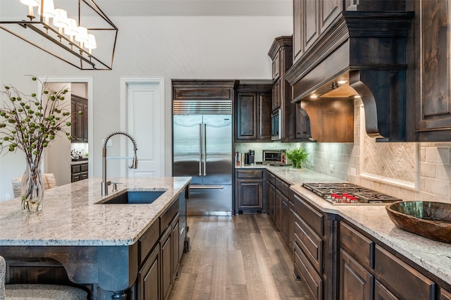 kitchen featuring a sink, dark brown cabinetry, dark wood-style floors, and stainless steel appliances