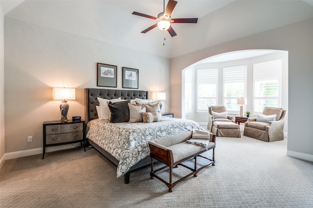 carpeted bedroom with baseboards, a ceiling fan, arched walkways, and high vaulted ceiling
