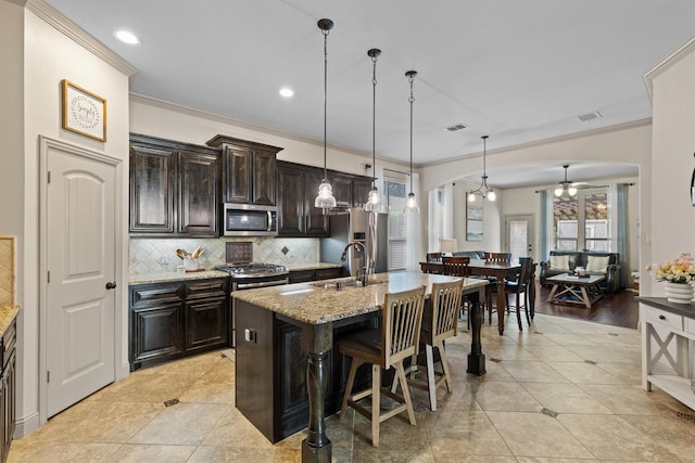 1711 Crescent Oak St, Wylie, TX 75098 - kitchen featuring appliances with stainless steel finishes, ornamental molding, a ceiling fan, a kitchen bar, and decorative backsplash