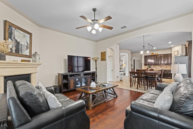 1711 Crescent Oak St, Wylie, TX 75098 - living room featuring arched walkways, a ceiling fan, dark wood finished floors, crown molding, and a fireplace