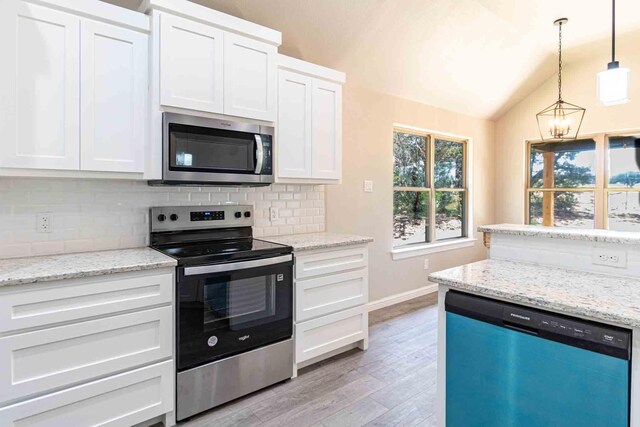 kitchen featuring stainless steel appliances, vaulted ceiling, white cabinetry, and tasteful backsplash