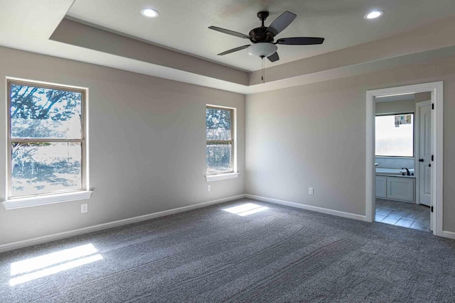 empty room featuring a raised ceiling, carpet floors, a ceiling fan, baseboards, and recessed lighting