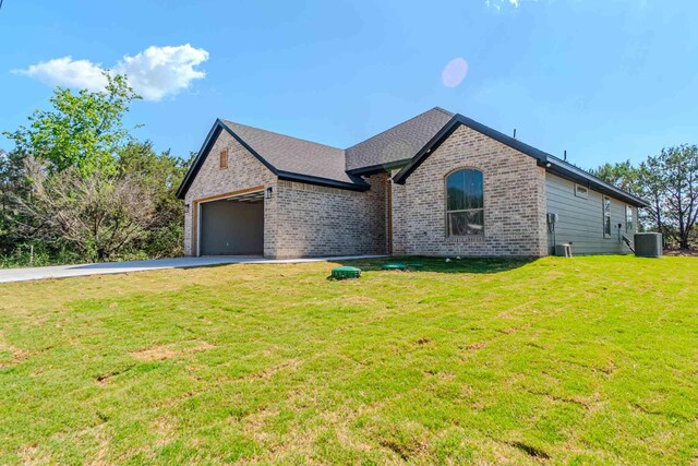 view of front of property with a garage, a front lawn, aphalt driveway, brick siding, and central AC unit