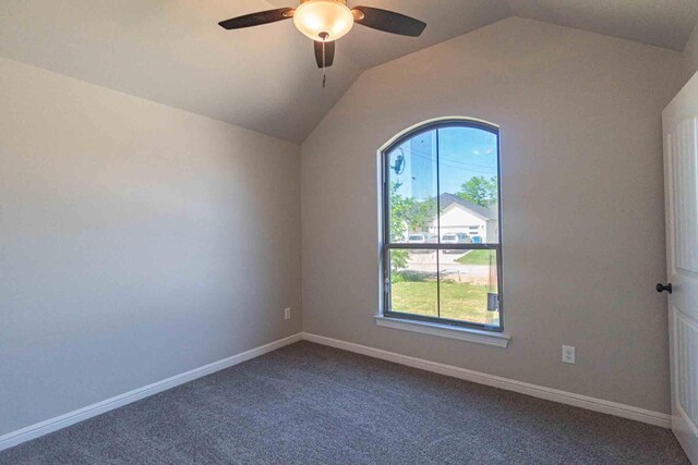 carpeted spare room featuring baseboards, ceiling fan, vaulted ceiling, and a wealth of natural light