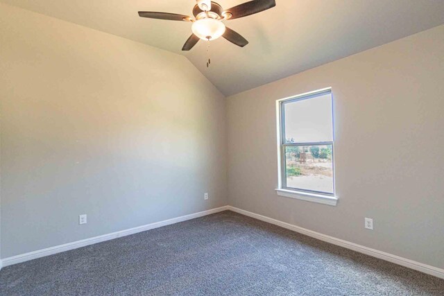 carpeted empty room featuring baseboards, a ceiling fan, and vaulted ceiling