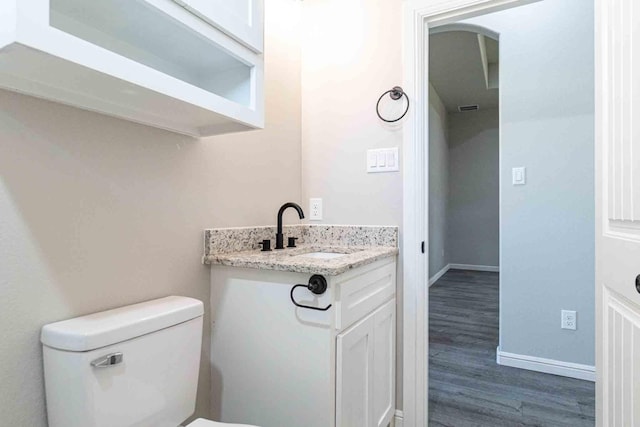 bathroom featuring toilet, baseboards, wood finished floors, and vanity