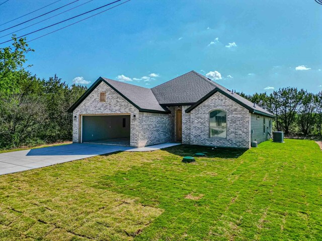 french provincial home featuring a garage, driveway, a front lawn, and brick siding