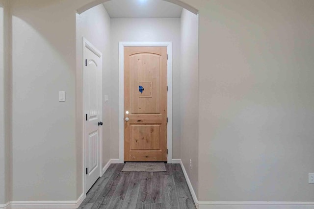 entryway with baseboards, arched walkways, and wood finished floors