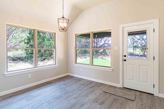 entryway featuring a healthy amount of sunlight, baseboards, wood finished floors, and a notable chandelier