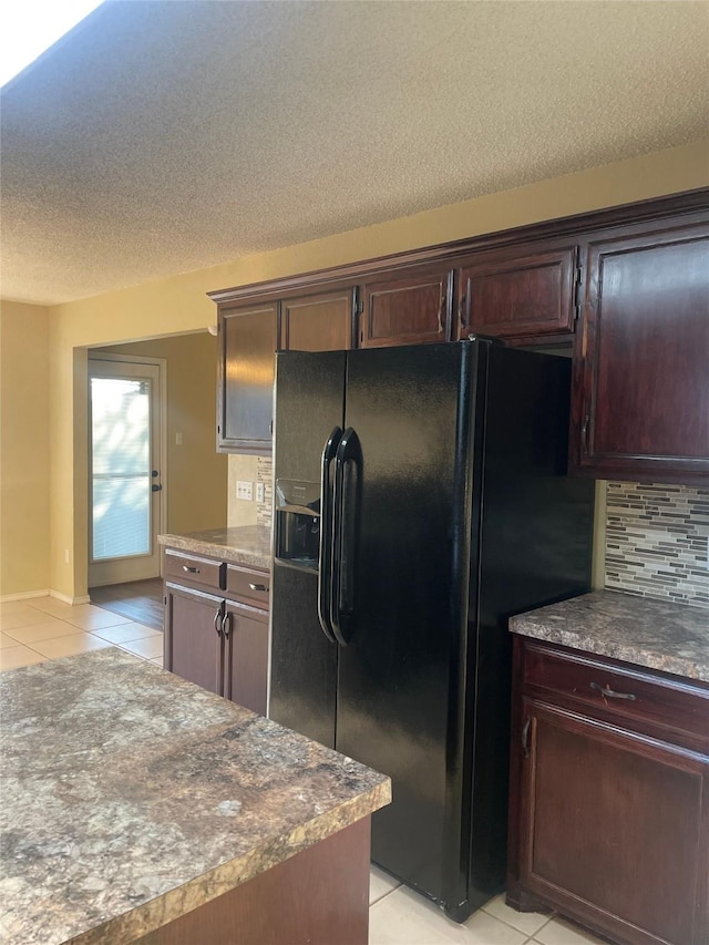 kitchen with backsplash, a textured ceiling, black fridge with ice dispenser, dark brown cabinets, and light tile patterned floors