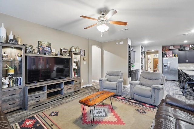 living room featuring visible vents, arched walkways, baseboards, and a ceiling fan