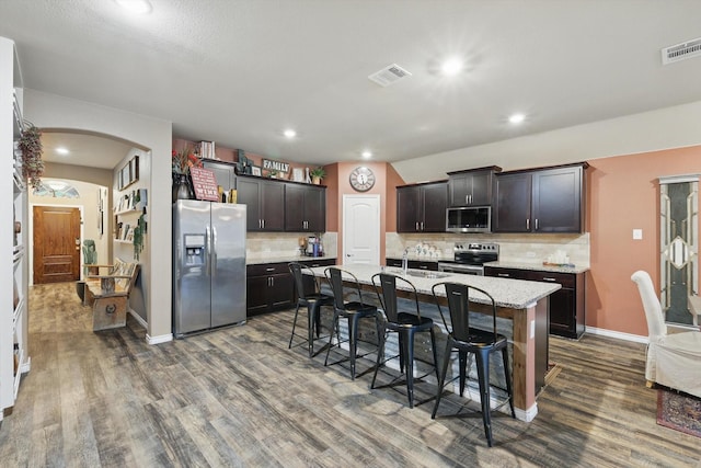 kitchen with a breakfast bar area, visible vents, arched walkways, dark wood-style floors, and stainless steel appliances