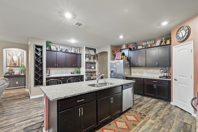 kitchen with arched walkways, appliances with stainless steel finishes, decorative backsplash, and a sink