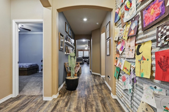 corridor featuring baseboards, arched walkways, and wood finished floors