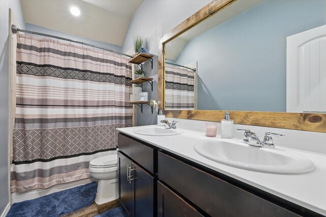 bathroom featuring double vanity, a sink, shower / tub combo with curtain, and toilet