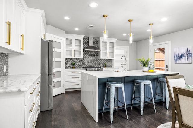 8911 Diceman Dr, Dallas, TX 75218 - kitchen featuring a breakfast bar area, backsplash, dark wood finished floors, freestanding refrigerator, and wall chimney exhaust hood