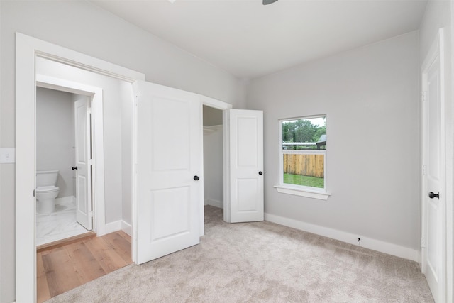 unfurnished bedroom featuring a closet, baseboards, carpet, and ensuite bath