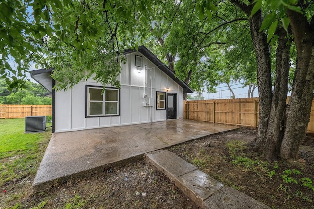 back of property featuring board and batten siding, fence, a patio area, and cooling unit