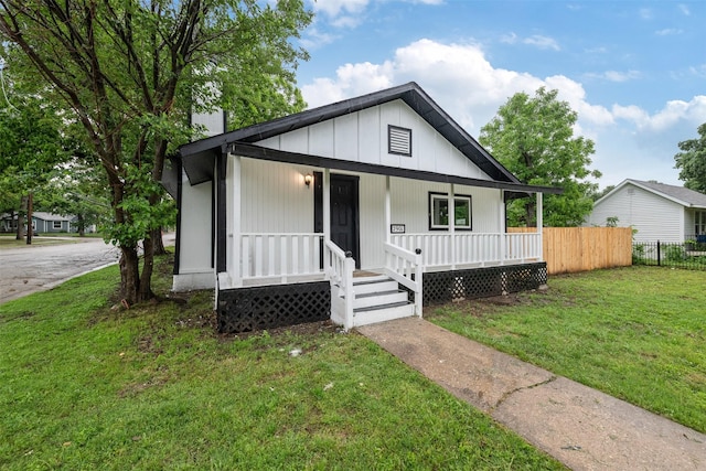 bungalow featuring fence, covered porch, and a front yard