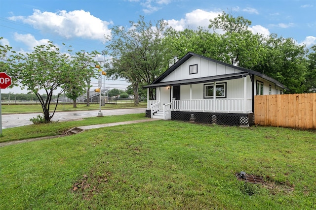 bungalow featuring fence, covered porch, concrete driveway, and a front lawn