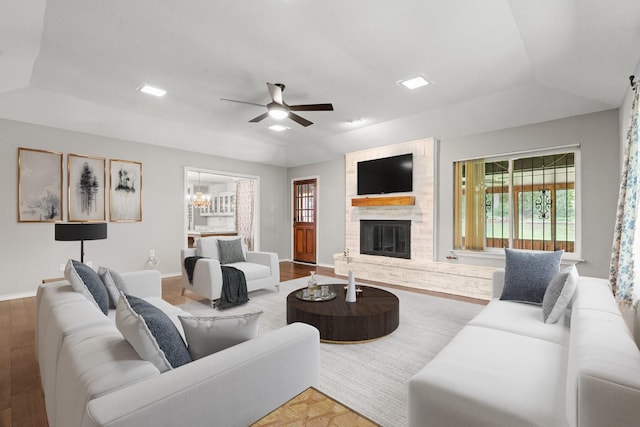 living room with baseboards, ceiling fan with notable chandelier, a large fireplace, and wood finished floors