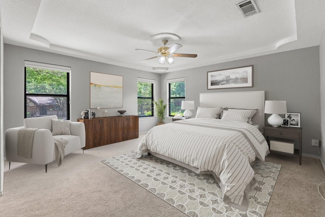bedroom featuring a textured ceiling, visible vents, light carpet, and multiple windows