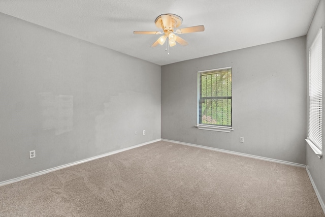 empty room featuring carpet floors, ceiling fan, and baseboards