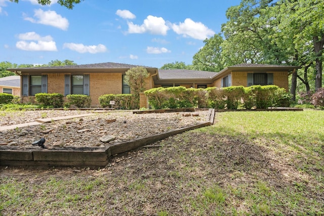 view of front facade with brick siding and a front lawn