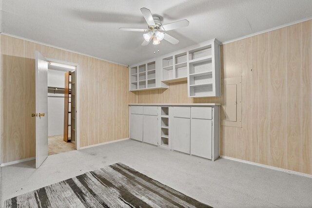 kitchen with crown molding, wooden walls, open shelves, ceiling fan, and light carpet