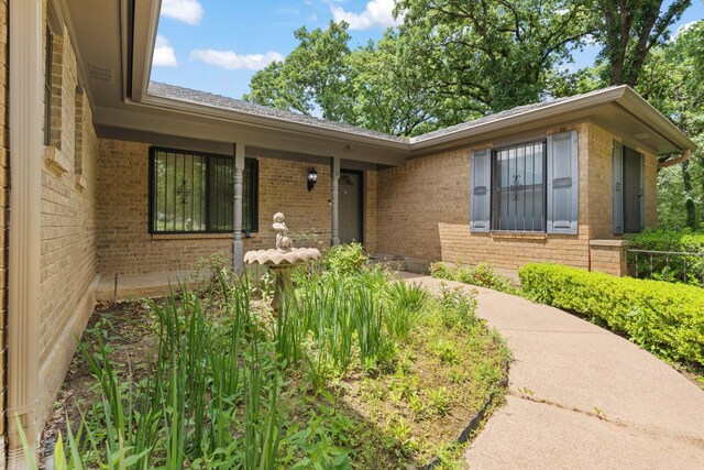 property entrance with brick siding and a shingled roof