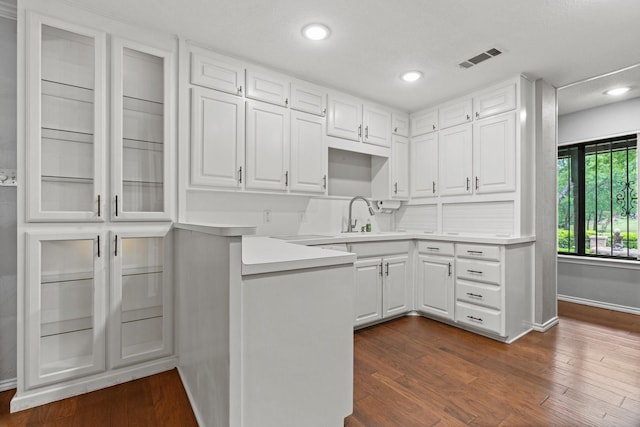 kitchen with dark wood-style flooring, visible vents, a sink, baseboards, and white cabinetry