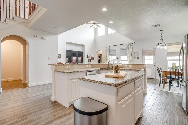 kitchen featuring arched walkways, visible vents, a healthy amount of sunlight, and a center island