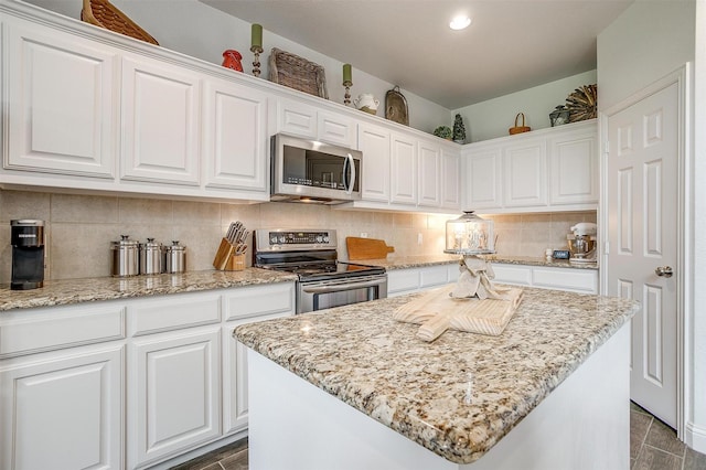 9820 Mullins Crossing Dr, Fort Worth, TX 76126 - kitchen featuring stainless steel appliances, white cabinetry, tasteful backsplash, light stone countertops, and a center island