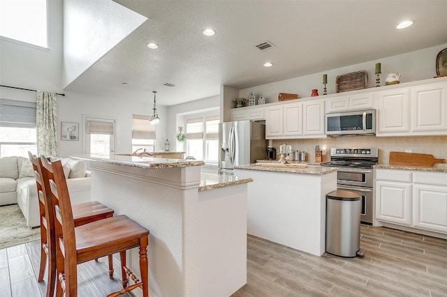 9820 Mullins Crossing Dr, Fort Worth, TX 76126 - kitchen with appliances with stainless steel finishes, a kitchen island, a kitchen breakfast bar, white cabinetry, and recessed lighting