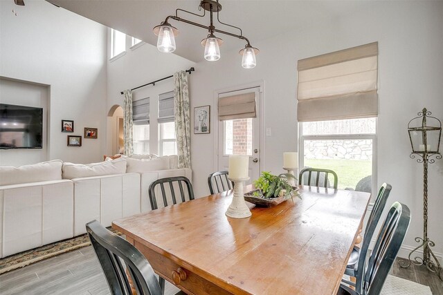 dining area with arched walkways and light wood-style floors