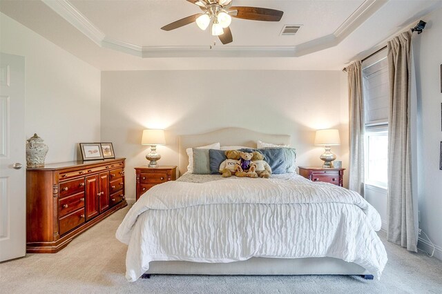 bedroom with visible vents, ornamental molding, a tray ceiling, and light carpet